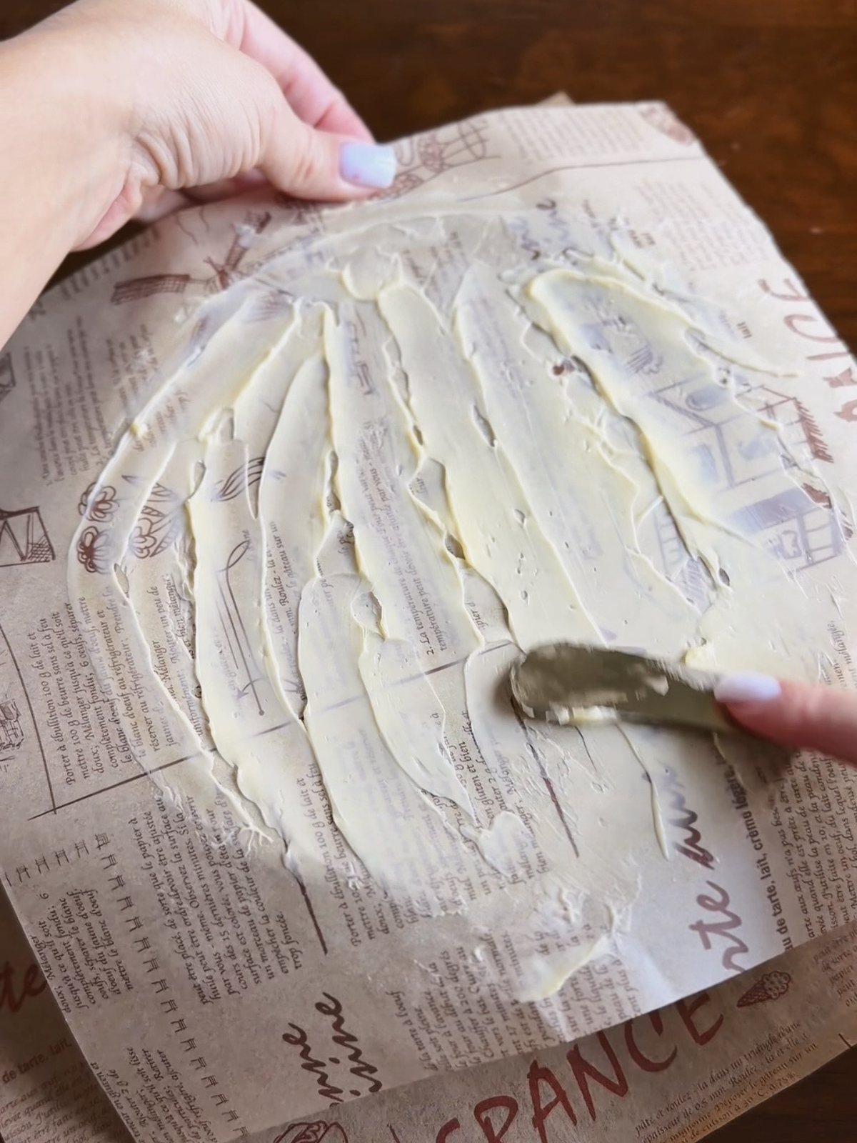 Spreading softened butter over parchment paper with an offset spatula to start an upside down puff pastry tart