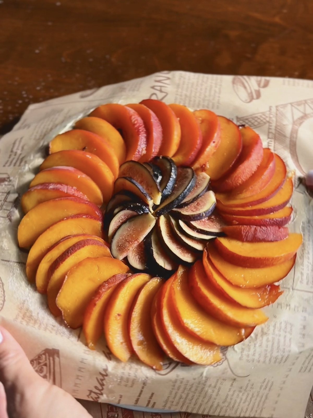 Sliced peaches in an overlapping ring with fresh figs in the center, ready to be covered with puff pastry