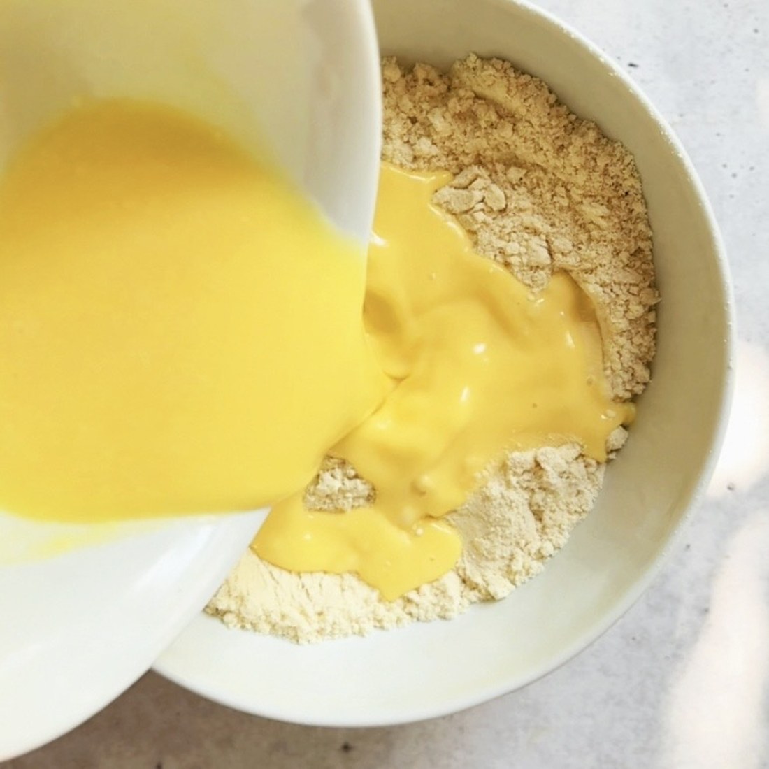 Pouring whisked eggs, melted butter and milk into the dry ingredients
