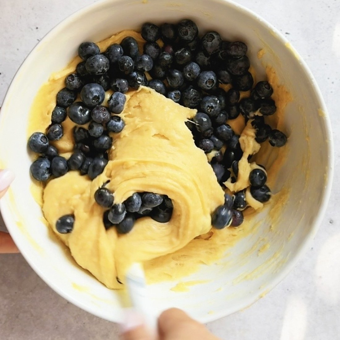 Folding two cups of fresh blueberries into the muffin batter