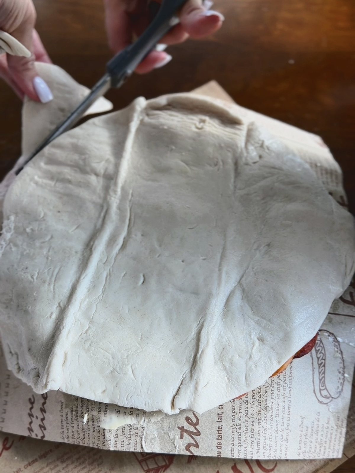 Trimming a sheet of puff pastry into a round over the arranged figs and peaches