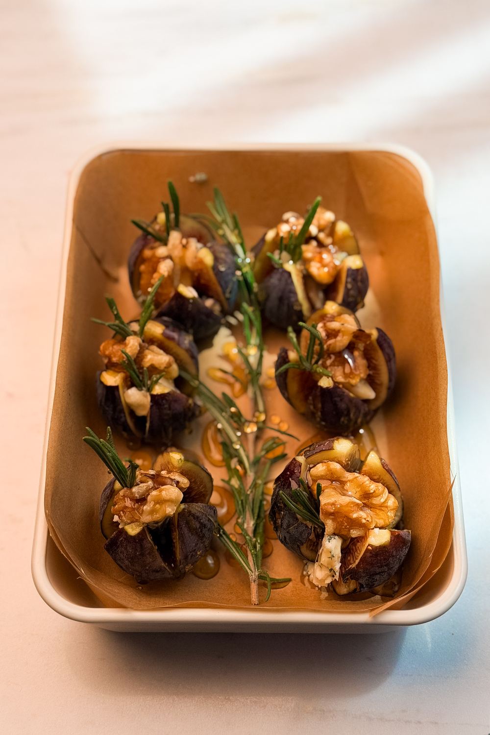 Stuffed figs after three minutes in the air fryer, warm and soft, with honey catching the light around a sprig of rosemary.