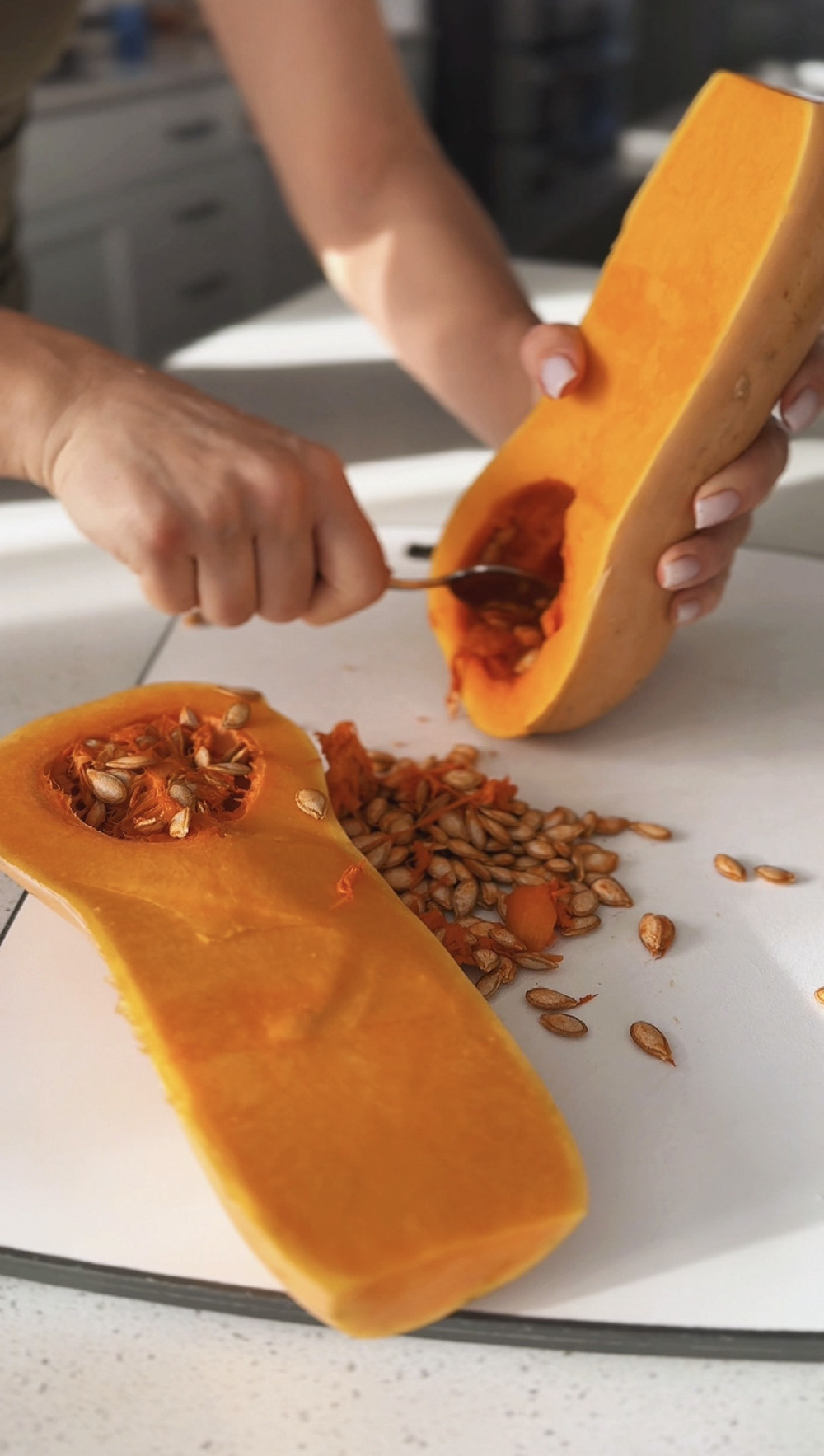 Scraping the seeds out of a halved butternut squash with a spoon