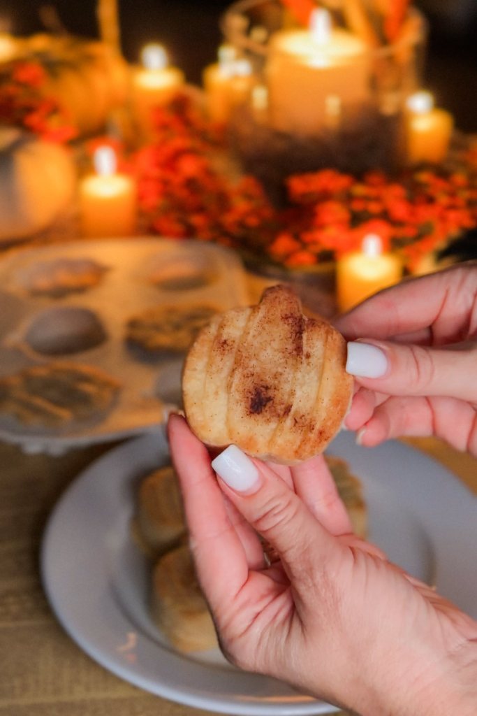 Pumpkin shaped shortbread cookie held above the silicone fall mold it was baked in