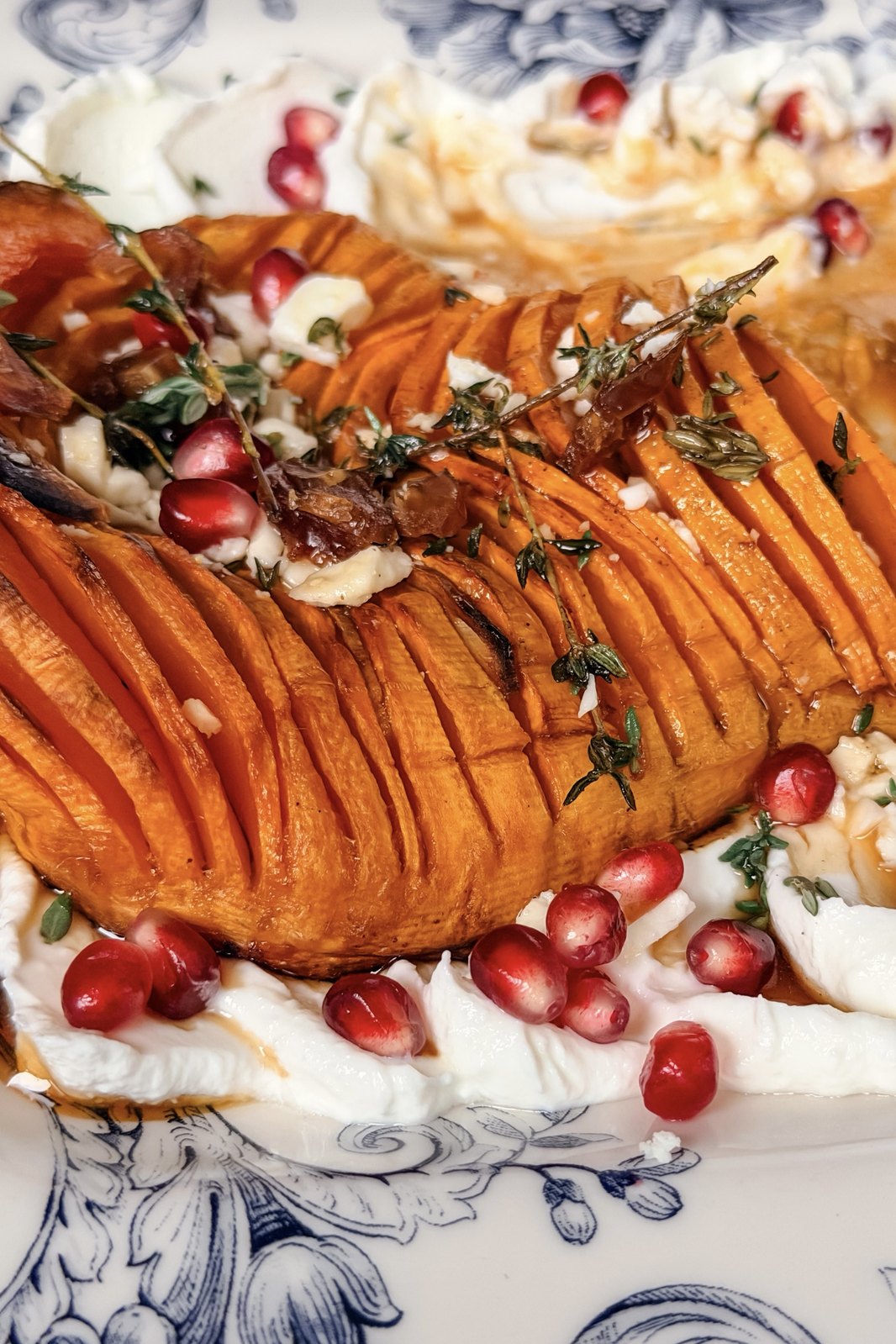 Caramelized edges of roasted hasselback butternut squash with pomegranate seeds and crumbled feta