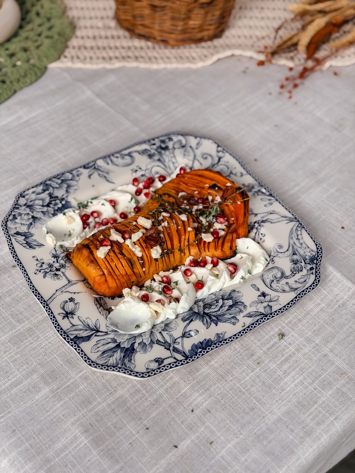 Hasselback butternut squash served on a blue and white platter on a set autumn table with candles and small pumpkins