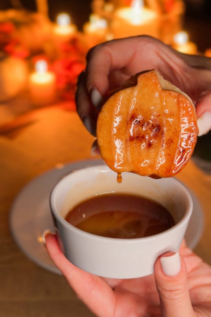 Pumpkin shortbread cookie glossy with maple syrup dripping back into the cup