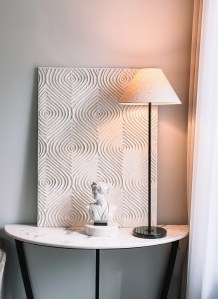 The marble console with the lamp, bust and carved panel