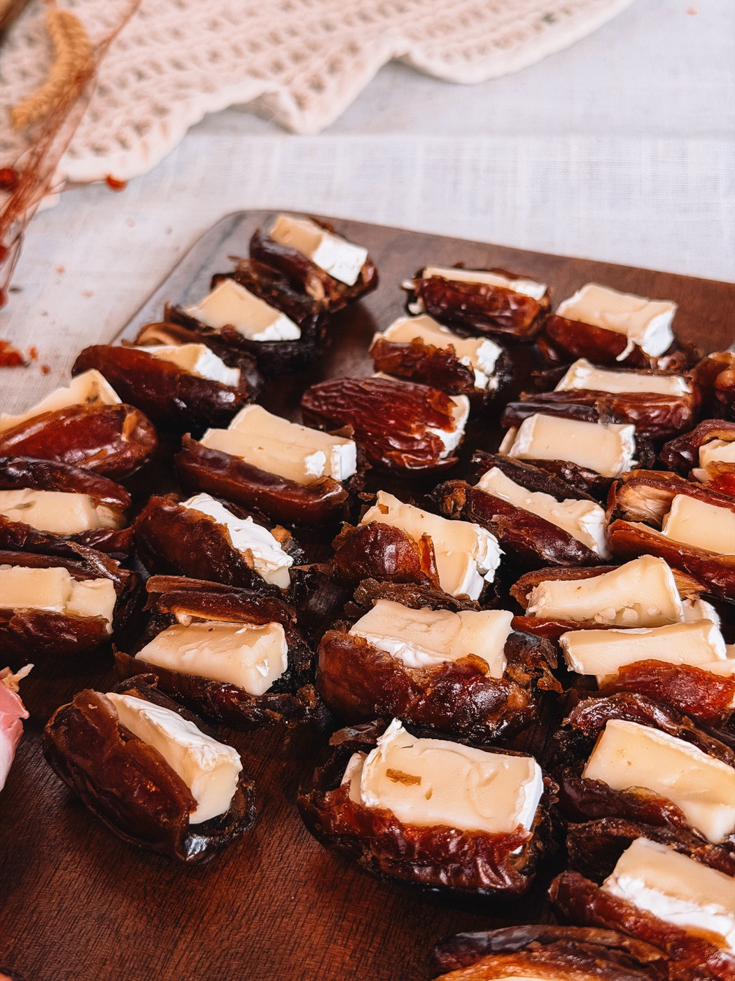 Medjool dates split open and filled with small pieces of brie on a wooden board