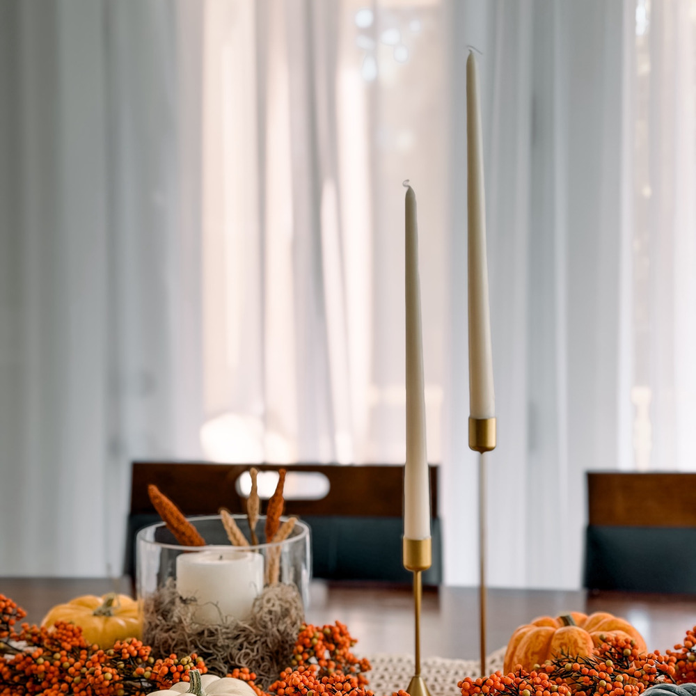 White taper candles in gold holders on a fall table
