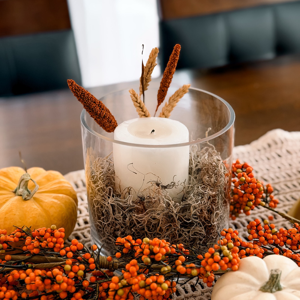Glass cylinder vase filled with Spanish moss, a white pillar candle and dried stems
