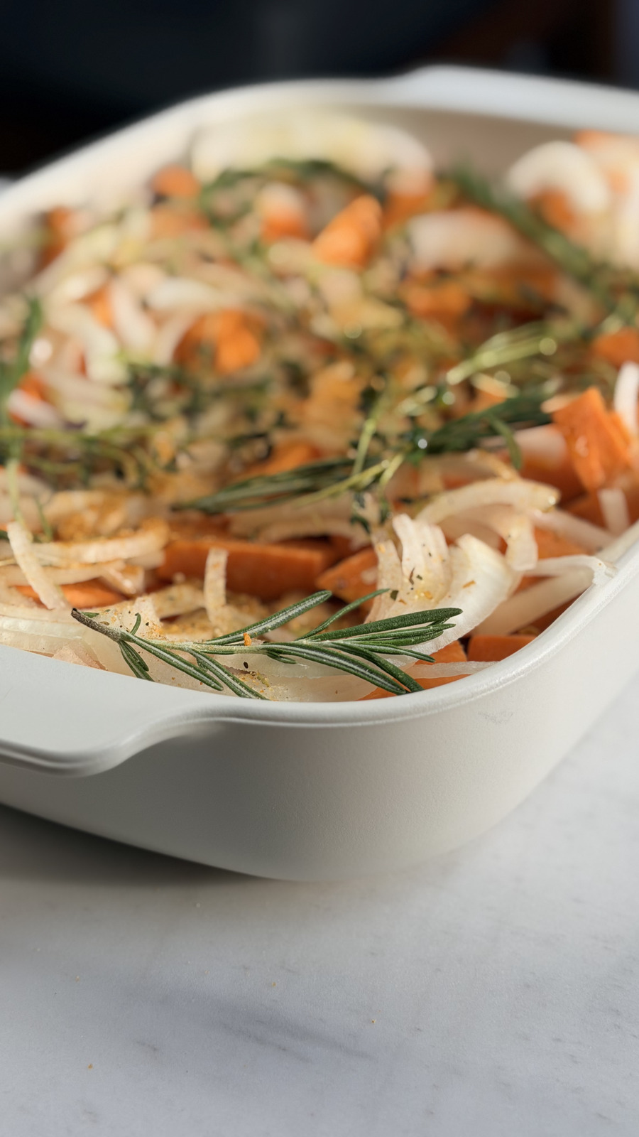 Close up of the baking dish filled with sweet potatoes, onion and herbs ready for the oven