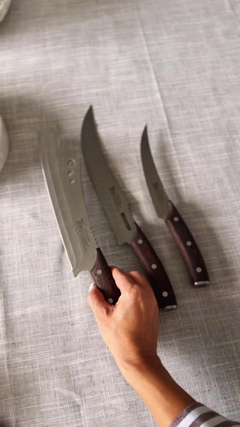 The three SYOKAMI butcher knives laid out side by side on a linen tablecloth